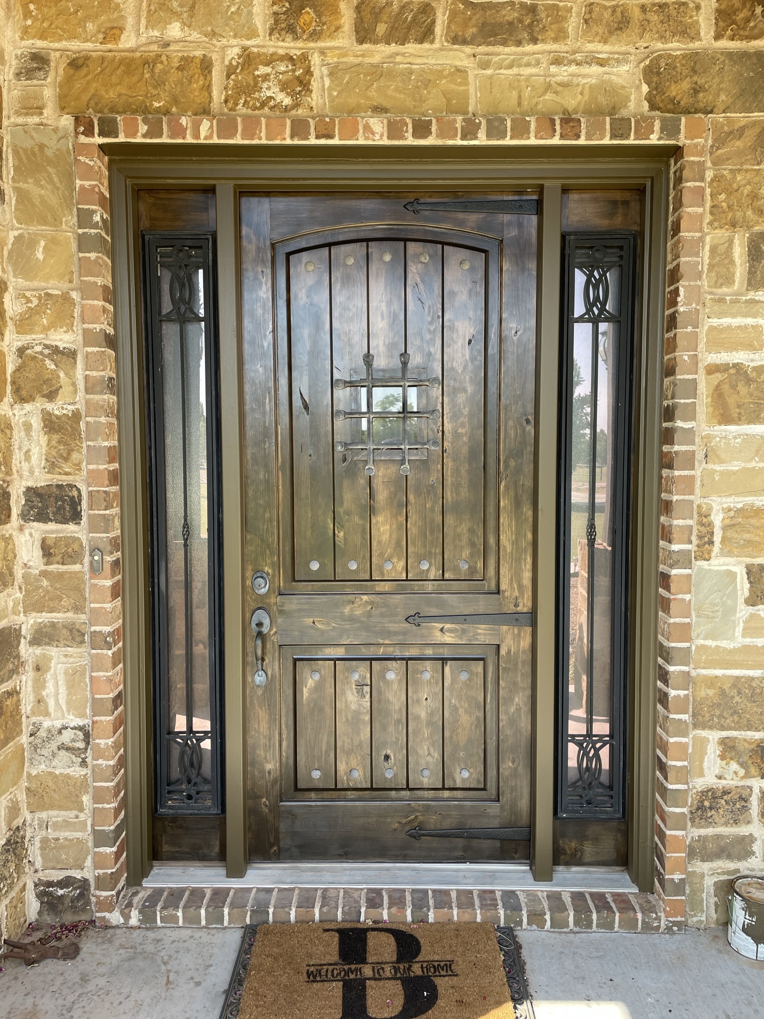 Beautiful dark stained arched front door on stone brick home