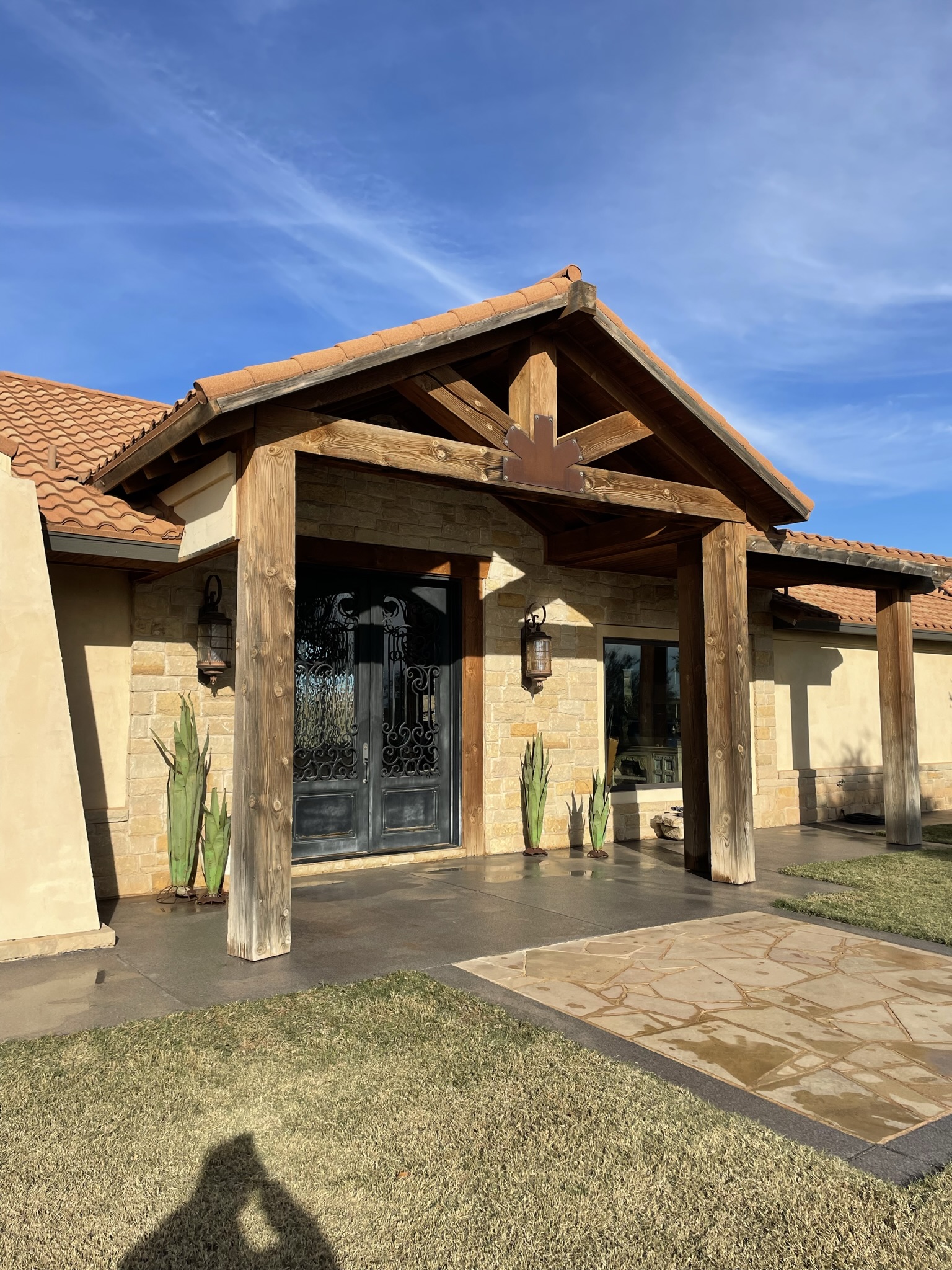 Beautiful stained cedar entry pergola on stone luxury home