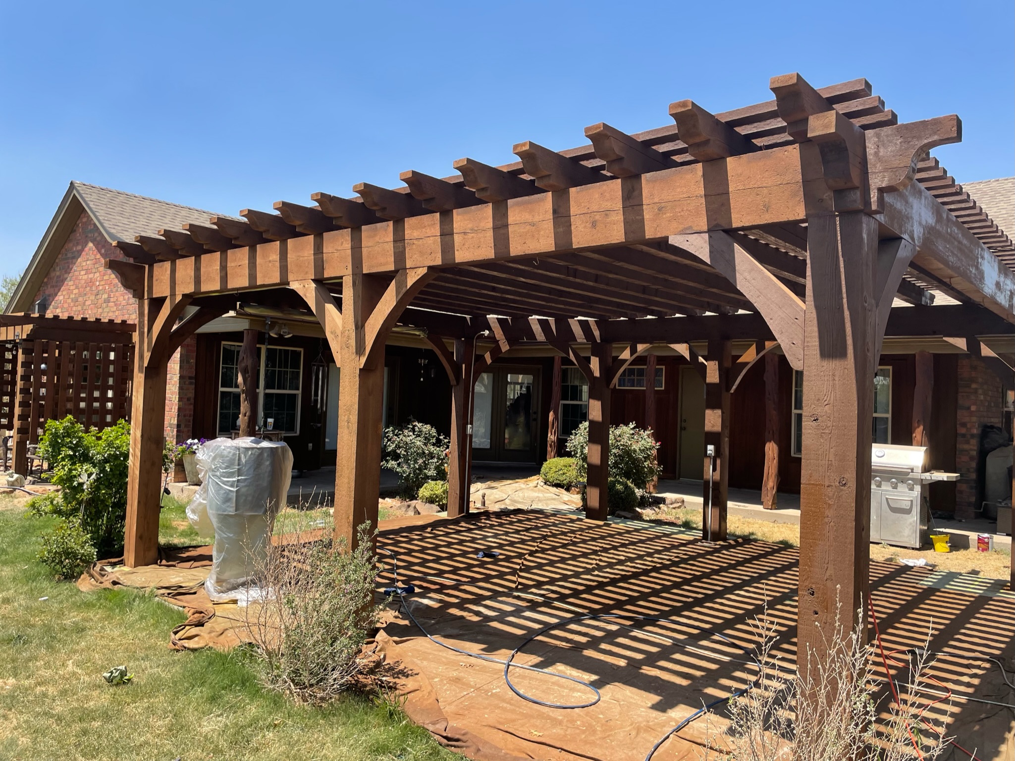 Custom pergola built over a backyard patio seating area