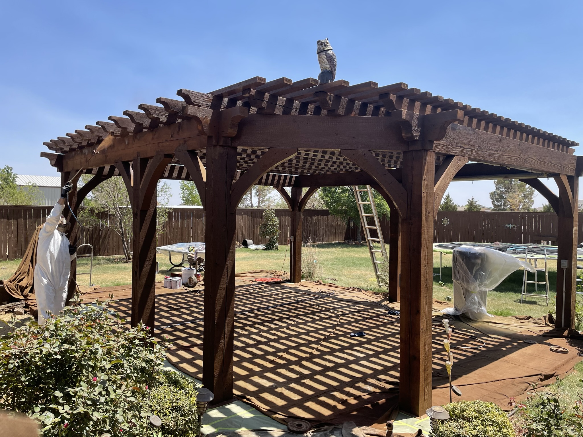 Custom wood pergola being stained dark brown